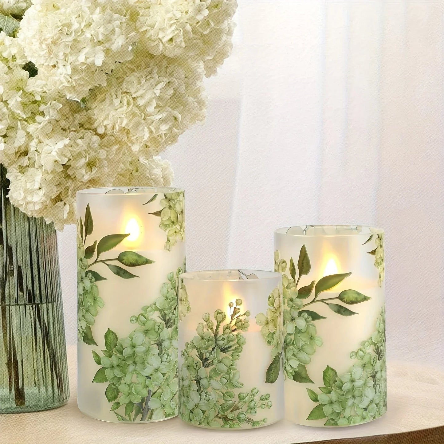 A set of 3 flameless candles, flickering LED pillar candles, with a 10-button remote control. They feature a green floral theme, are suitable for spring and summer, and can be used on the dining tables at wedding venues